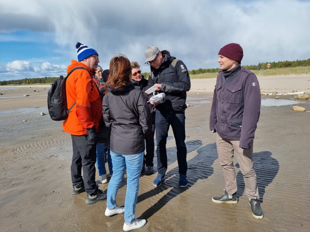 People standing on the beach gathered around the drone