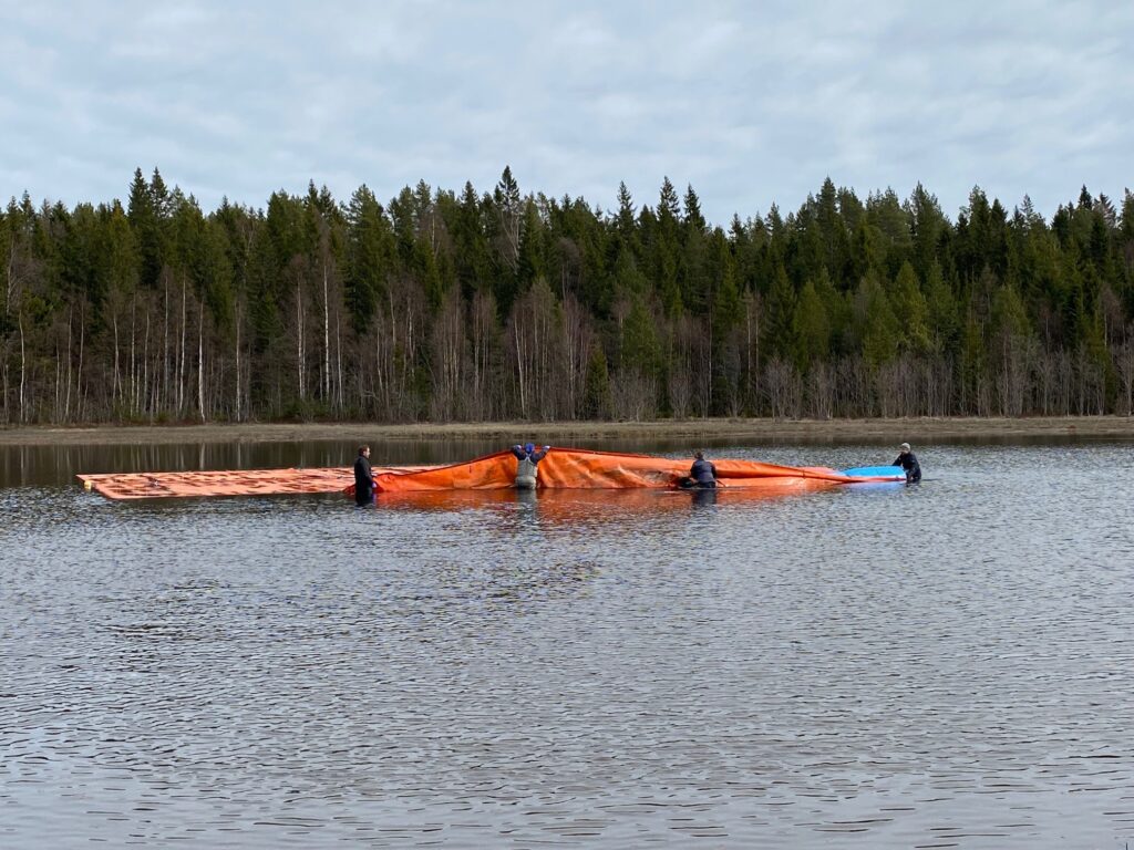 Large, orange mat floating on the water held by snorkelers