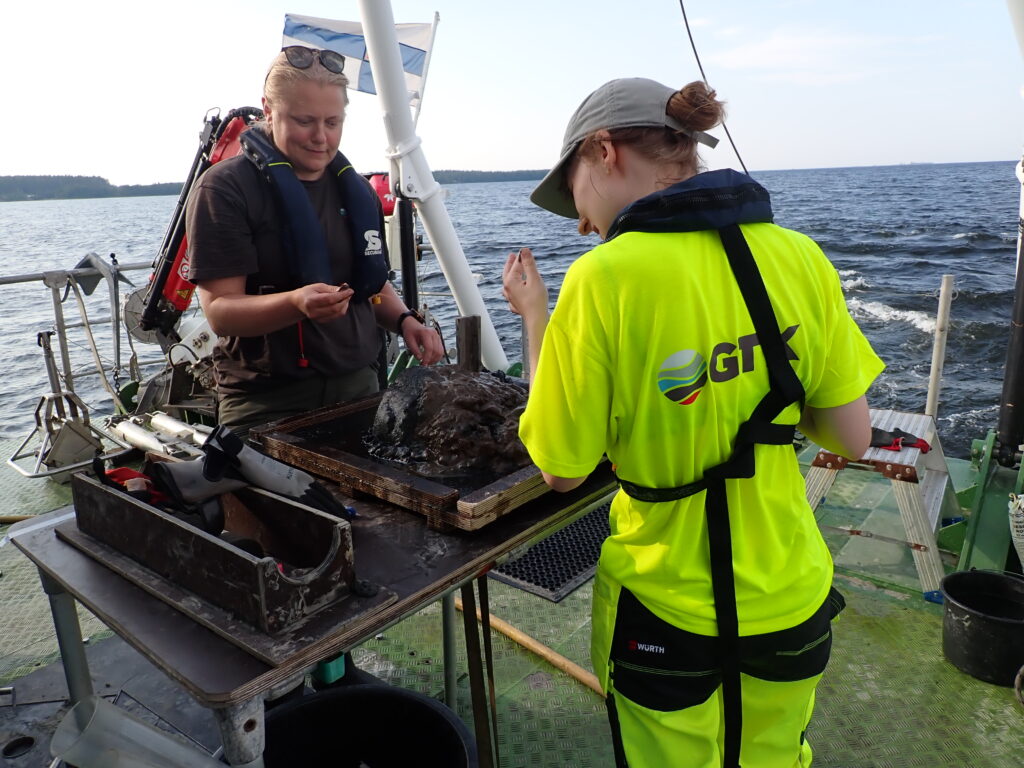 Two persons on deck looking at sediment sample